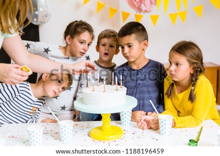 Kids are preparing to blow candles on birthday cake