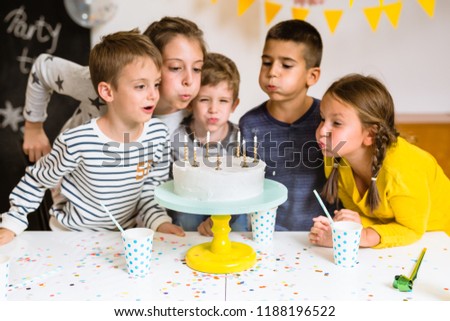 Kids blowing birthday cake candles