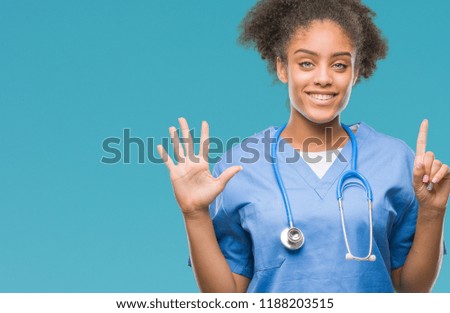 Young afro american doctor woman over isolated background showing and pointing up with fingers number six while smiling confident and happy.