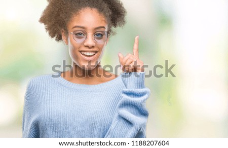 Young afro american woman wearing glasses over isolated background pointing finger up with successful idea. Exited and happy. Number one.