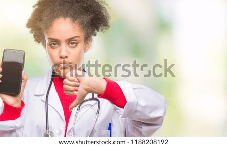 Young afro american doctor woman using smartphone over isolated background with angry face, negative sign showing dislike with thumbs down, rejection concept