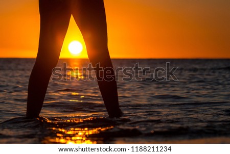 Closeup photo of a women's feet over background of a beautiful orange sunset over sea, pleasure and relaxation, summer vacation concept