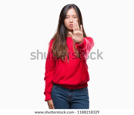Young asian woman wearing winter sweater over isolated background doing stop sing with palm of the hand. Warning expression with negative and serious gesture on the face.