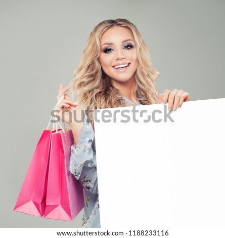 Young woman holding pink shopping bags and white empty board banner background