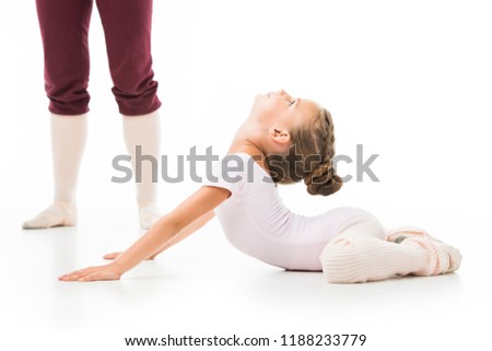 cropped image of female trainer in pointe shoes standing near little ballerina while she stretching isolated on white background 