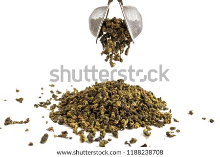 Chinese green teguanin tea, scattered on a white background, poured with a tea spatula and a tea filter..