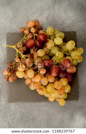 bunches of ripe grapes on slate stone and gray background