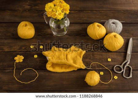 Knitted kids wear of yellow color on a dark wooden background