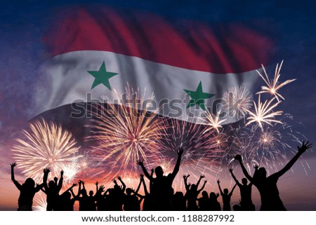 Happy people are looking holiday fireworks with flag of Syria in sky, independence day