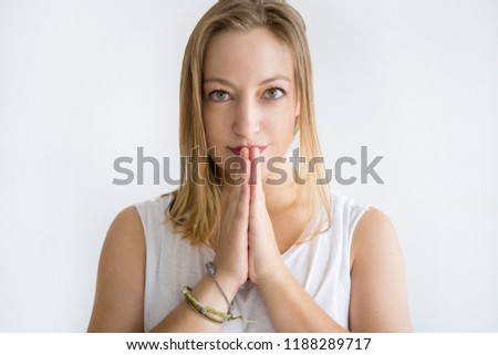 Serious woman keeping hands together and begging for something. Young lady looking at camera. Request concept. Isolated front view on white background.