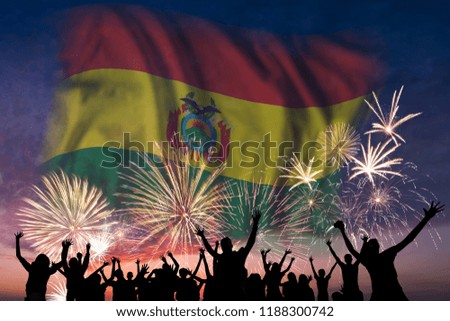 Happy people are looking holiday fireworks with flag of Bolivia in sky, independence day