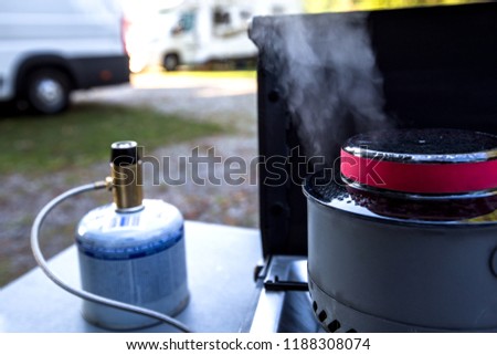 Boiling water on a camping stove. Gas stove with gas cartridge on a camp site in the mountains. Outdoor kitchen in the holidays. 