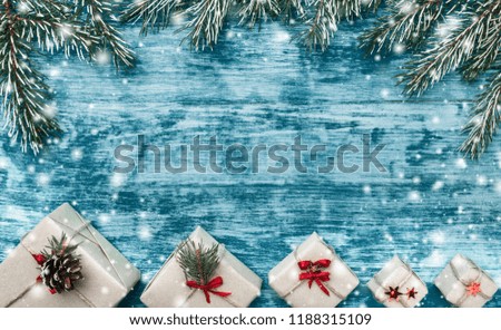Christmas azure background with handmade gifts and fir branches at the top of the picture. Space for text. Top view. Snow effect.