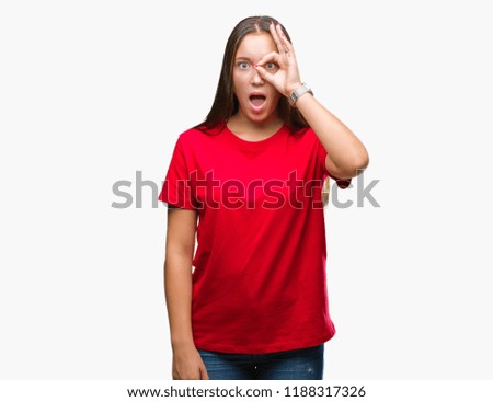 Young beautiful caucasian woman over isolated background doing ok gesture shocked with surprised face, eye looking through fingers. Unbelieving expression.