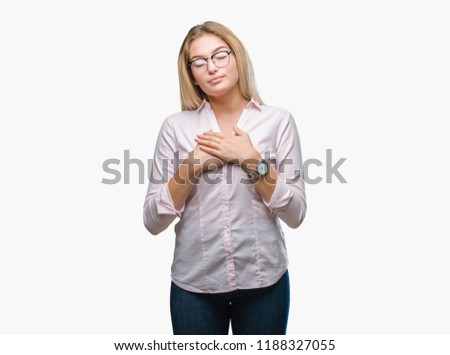 Young caucasian business woman wearing glasses over isolated background smiling with hands on chest with closed eyes and grateful gesture on face. Health concept.