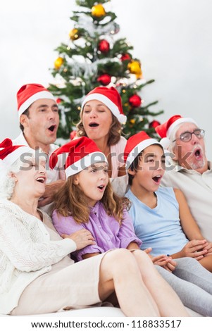 Extended family singing christmas carols together on couch