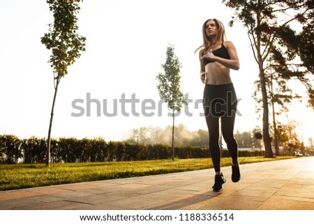 
A sporty girl is running around in the park in the morning. Outdoor sport. Morning run. Sunlight background.