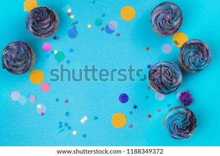 Vanilla cupcakes with galaxy dark whipped cream on party background with blank space for text