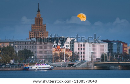 
Full moon over the Riga old town. Panoramic scene with colorful full moon over the city at blue hour. Historical bridge, buildings and skyscraper creating the scene.
