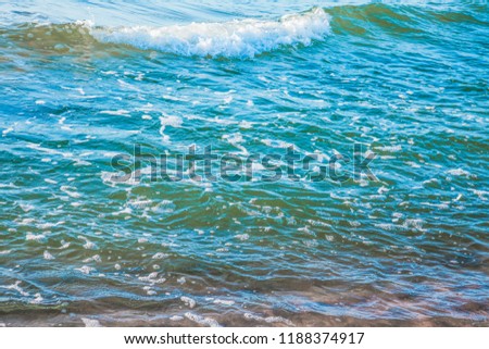 pure azure clear water with white foam on the sea on a sunny afternoon, blurry background