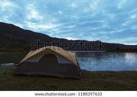 Camp, camping tent in sunset and sunrise in nature. Royalty high-quality free stock image of adventures camping and tent on grass, lake and mountain landscape. Outdoor camping vacation in the natural