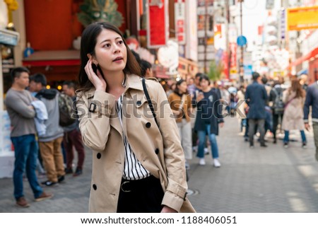 pretty lady standing in the busy street and choosing which store she wants to shop