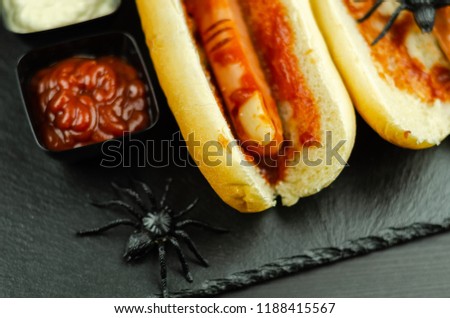 Creepy Halloween hotdog fingers on the black table, party food