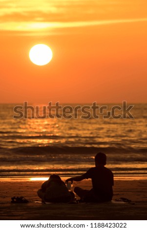 A Silhouette lover couple are enjoying beautiful nature sunset sun down at Tanjung Aru Beach, Kota Kinabalu, Sabah, Borneo 