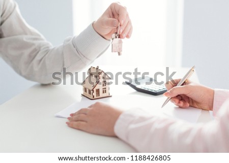real estate agent holding house key to his client after signing contract,concept for real estate, moving home or renting property