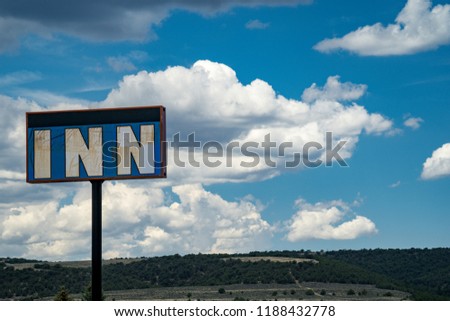 Generic sign for an abandoned Inn motel or hotel against a partly cloudy summer sky