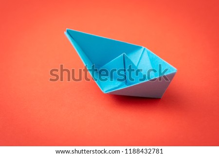 Red ocean business competition, survive success or winner company metaphor concept, blue origami paper ship on red background as ocean in minimal style.