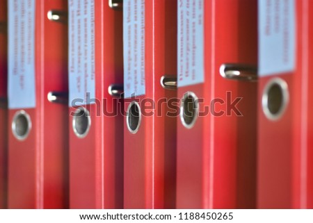 Red large folders files with inscriptions for storing office documents stand vertically on shelf Royalty-Free Stock Photo #1188450265