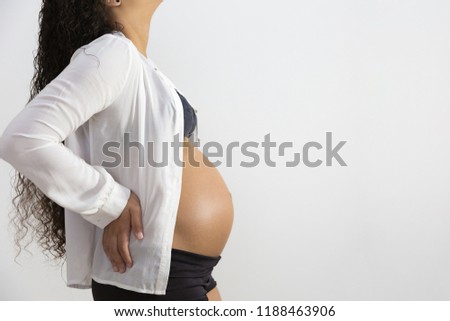 Close-up studio shoot of pregnant woman touching her belly. Isolated on white background