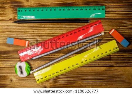 Set of school stationery supplies. Rulers, pencils, erasers and sharpener on wooden desk. Top view