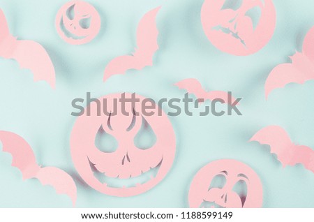 Halloween background - pink spooky faces emoji and bats of cut paper on pastel trendy mint blue color, pattern.