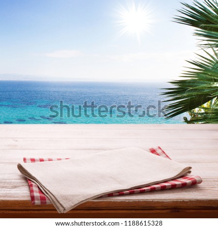 Napkin and tablecloth on wooden table and summer sea background. Top view mockup