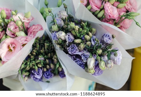 beautiful tender blue and pink roses bouquets in paper package at the street flower market in sunny summer day