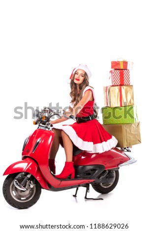 happy brunette girl in santa costume driving red scooter with presents, isolated on white