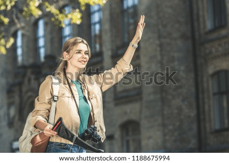 portrait of young traveler with backpack, photo camera and map calling taxi on street