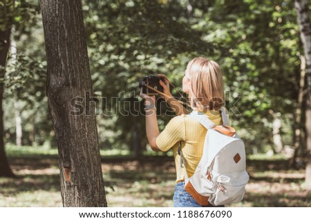 rear view of tourist taking picture on photo camera in park