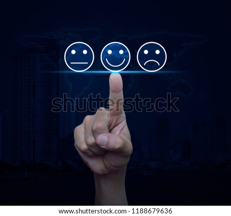 Hand pressing excellent smiley face rating icon over world map and modern city tower, Business customer service evaluation and feedback rating concept, Elements of this image furnished by NASA