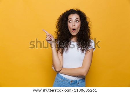 Photo of shocked excited young cute woman posing isolated over yellow background pointing.