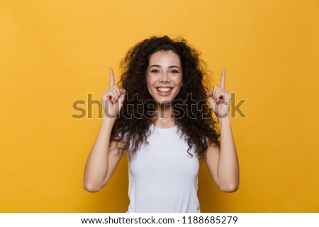 Photo of beautiful excited young cute woman posing isolated over yellow background pointing.