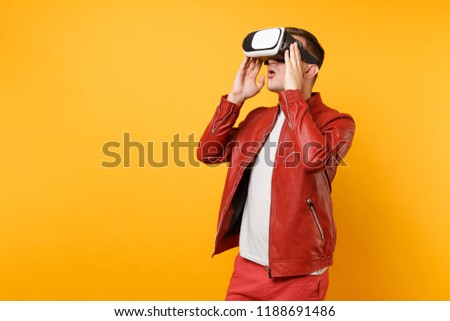 Portrait vogue fun young man in red leather jacket t-shirt looking up in headset standing isolated on bright trending yellow background. People sincere emotions lifestyle concept. Advertising area