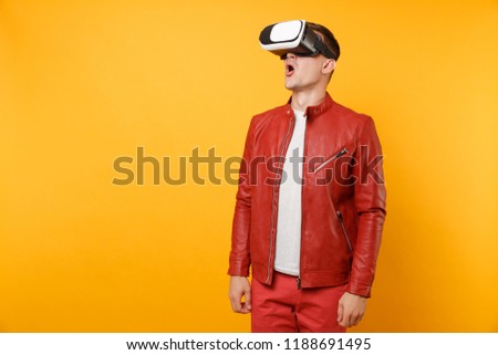 Portrait vogue handsome young man in red leather jacket, t-shirt looking in headset standing isolated on bright trending yellow background. People sincere emotions lifestyle concept. Advertising area