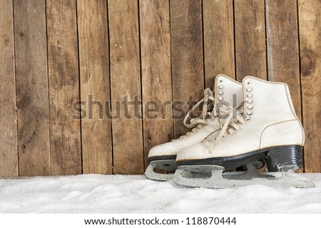old ice skates against an weathered wooden wall