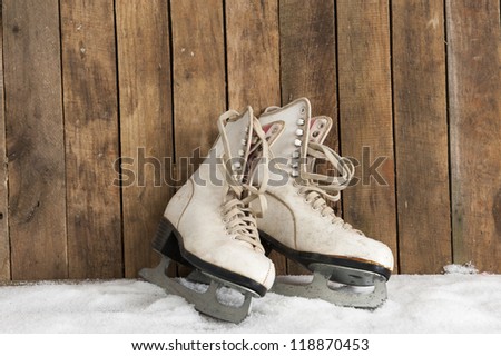 old ice skates against an weathered wooden wall