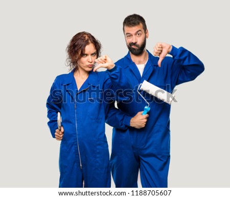 Painters showing thumb down sign with negative expression on isolated grey background