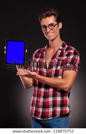 young casual fashion man presenting a new tablet pad on dark background