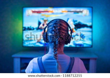 A girl is a gamer or a streamer in front of a television playing.It is possible to use as a background
